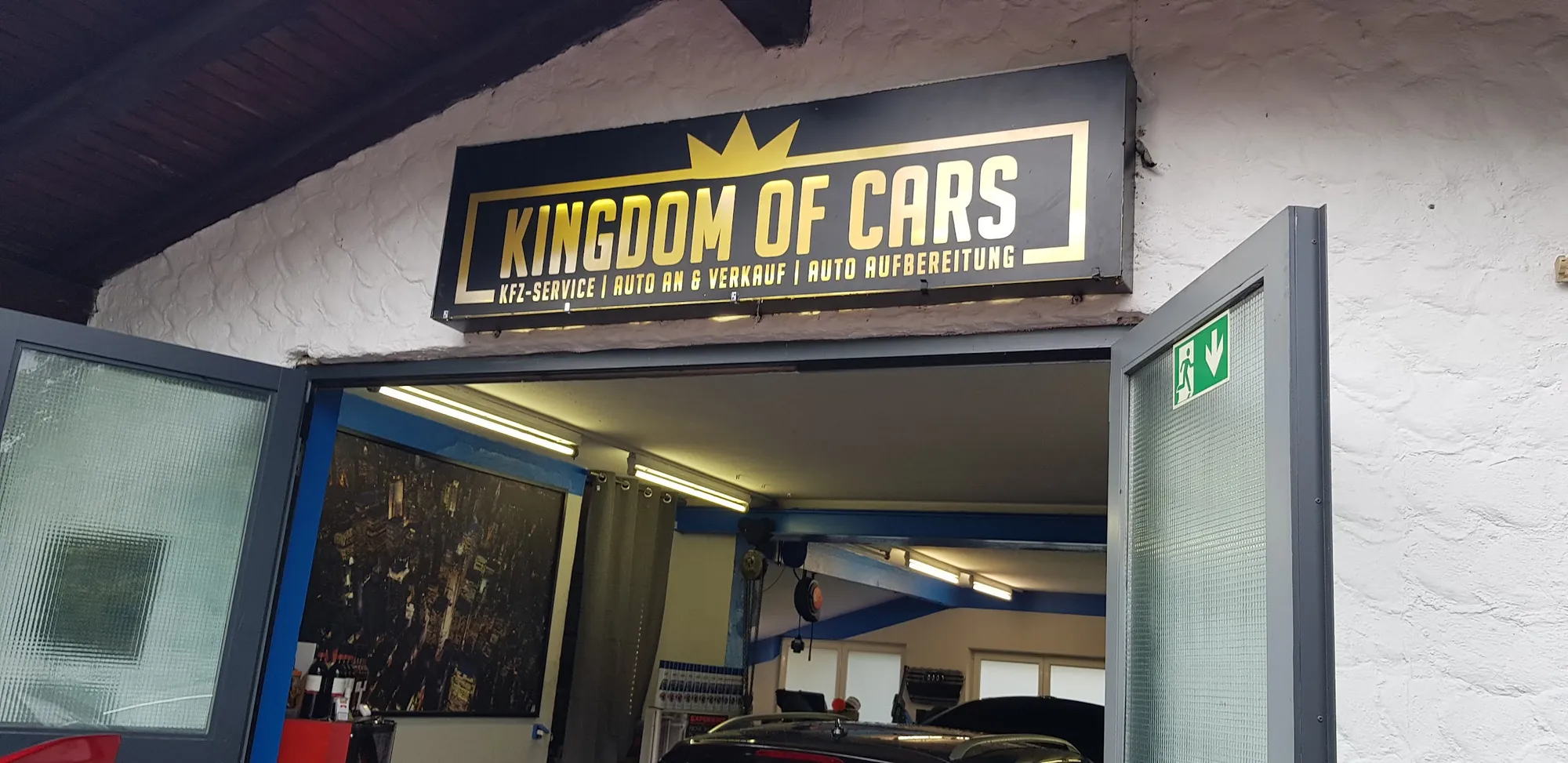 Eingang der Werkstatt mit dem schwarz-goldenen Schild Kingdom of Cars
